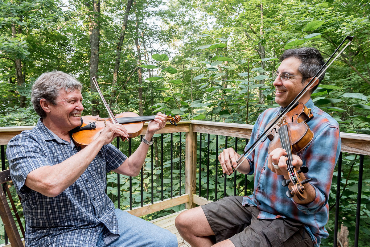 Middle aged male student enjoying fiddle lesson on the back deck with Michael