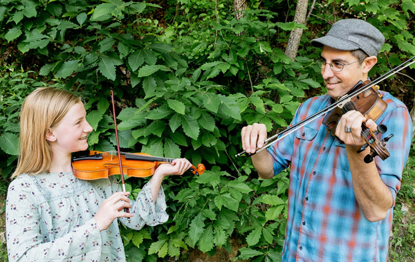 Fiddle instructor teaching a young student outdoors